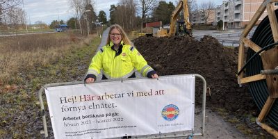 Tjej står på cykelväg bakom ett byggstaket