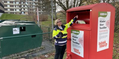 Kvinna slänger plastpåse med kläder i textilåtervinning